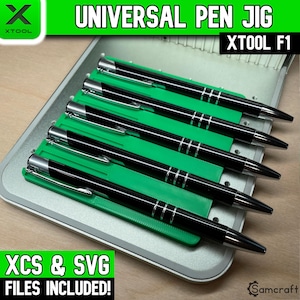 May include: A green plastic universal pen jig for the xTool F1 laser engraver, featuring five parallel slots holding black pens with silver accents. The text Universal Pen Jig, xTool F1, and XCS & SVG Files Included is visible on the image.