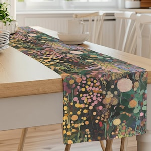 May include: A floral table runner with a dark green background and a variety of colourful flowers in pink, yellow, and white. The runner is made of fabric and has a subtle sheen.