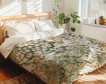 May include: A bed with white bedding and a green and gold patterned duvet cover. The duvet cover has a subtle abstract pattern with a hint of leopard print.