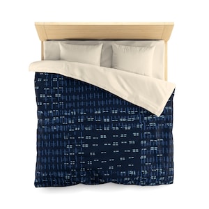 May include: A navy blue duvet cover with a geometric pattern of white and blue lines. The duvet cover is on a bed with white pillowcases.