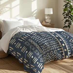 Könnte beinhalten: Ein dunkelblauer Bettbezug mit einem weißen geometrischen Muster. Der Bettbezug liegt auf einem Bett mit weißen Kissen und einem Nachttisch aus Holz.