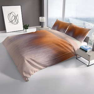 Pode incluir: Uma capa de edredom bege com um padrão degradê laranja e roxo sutil. A capa de edredom é feita de tecido macio e respirável, perfeita para um quarto moderno.