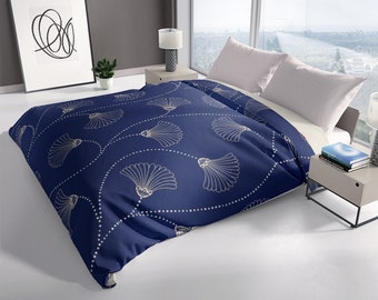 May include: A navy blue duvet cover with a white and gold pattern of stylized seashells. The duvet cover is on a bed with white pillows.