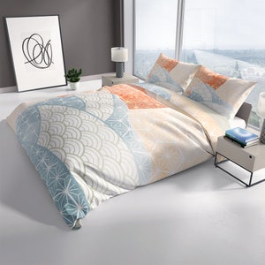 May include: A white duvet cover with a geometric pattern in shades of blue, orange, and beige. The pattern features a repeating design of overlapping circles, stars, and waves.