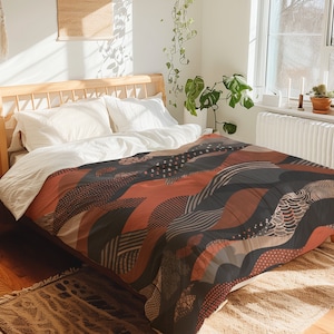 May include: A bed with a brown, black, and white patterned duvet cover. The duvet cover features geometric shapes and abstract designs.