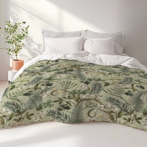 May include: A green duvet cover with a floral pattern featuring ferns, leaves, and white flowers. The duvet cover is on a bed with white pillows.