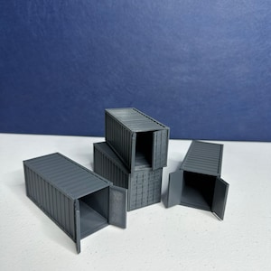 May include: Four gray miniature shipping containers with doors that open. The containers are stacked on top of each other.