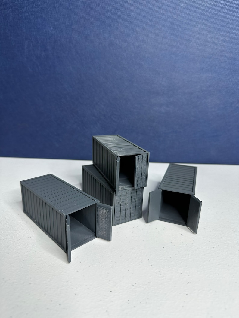 May include: Four gray miniature shipping containers with doors that open. The containers are stacked on top of each other.
