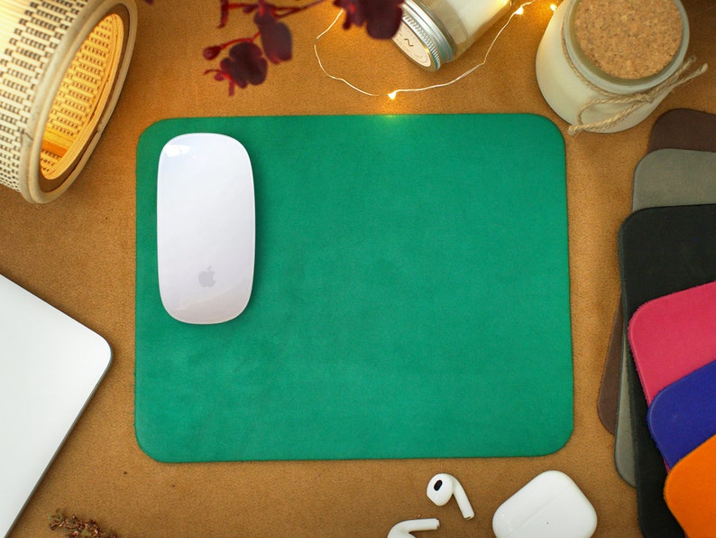 Peut inclure: Un tapis de souris vert avec une souris sans fil blanche sur le dessus. Le tapis de souris est sur une surface brune avec une lampe blanche, un bocal en verre et une bougie en arri&egrave;re-plan.