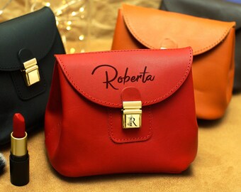 May include: Three leather cosmetic bags in red, orange and black. The red bag has the name Roberta embossed on the front.