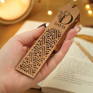 May include: A wooden bookmark with a geometric design and a tassel. The bookmark is personalized with the letter "D" and the name "DAVIS".