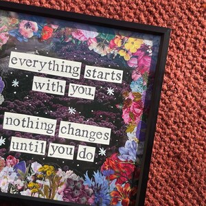以下が含まれることがあります： 花柄の縁取りと「everything starts with you, nothing changes until you do」というテキストが入った額装されたアート作品。この作品は、暗い背景、白い文字、カラフルな花が特徴です。