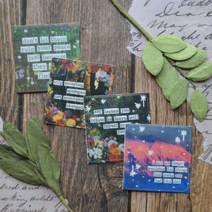 May include: A collection of square art prints with inspirational quotes. The prints feature floral and celestial backgrounds with white text. A green leaf and a sprig of leaves are also in the image.