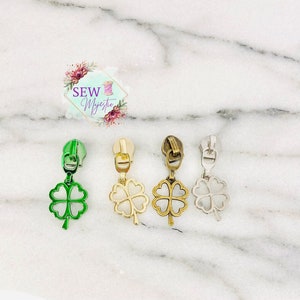 May include: Four zipper pulls with four-leaf clover charms. The charms are in green, gold, bronze, and silver.