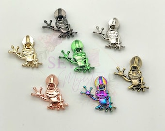 May include: Assortment of zipper pulls featuring a frog design in various metallic finishes, including gold, silver, green, rose gold, and iridescent.