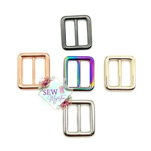 Puede incluir: Cinco hebillas deslizantes de metal en diferentes acabados: negro, arcoíris, oro rosa, oro y plata. Las hebillas son de forma cuadrada con una abertura rectangular en el centro.