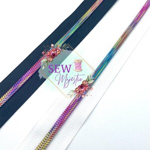 May include: Close-up of two zippers, one navy blue and one white, each with a rainbow-colored metallic zipper tape. The zippers are angled across the frame. The image includes the text "SEW Majestic" with floral accents.