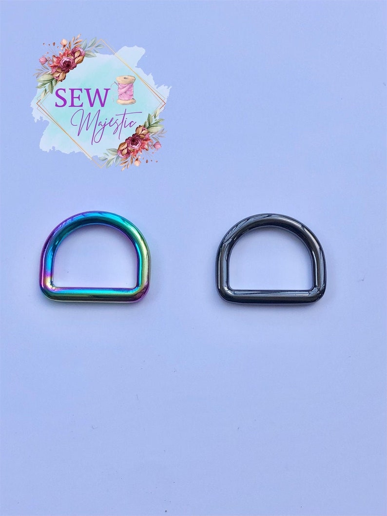 Puede incluir: Dos anillos en D de metal, uno con un acabado arco&iacute;ris iridiscente y otro con un acabado negro.