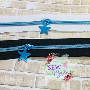 May include: Two zipper pulls with blue metal star charms. The zipper pulls are on white and black fabric.