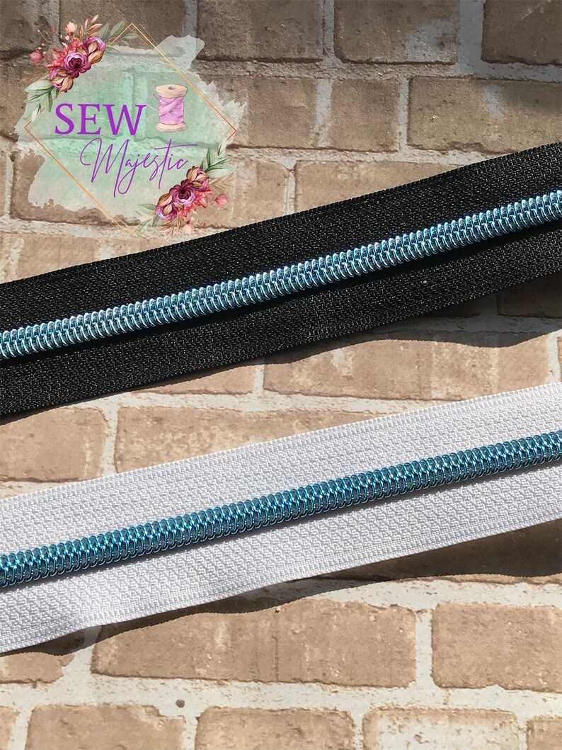 May include: Two zipper tapes with a blue metallic zipper teeth. The tape on top is black and the tape on the bottom is white.