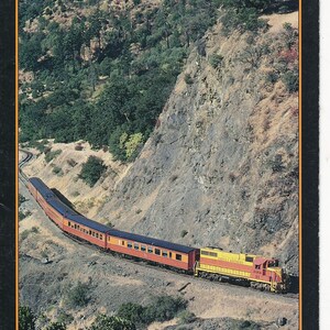 Pode incluir: Um cartaz de viagem vintage para as excursões ferroviárias North Coast Daylight, com um trem viajando por uma paisagem montanhosa com o texto "Leave the road signs behind." e "Willits-Eureka".
