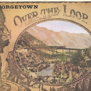 Peut inclure: Une carte postale vintage représentant une vue panoramique d'un train traversant un pont au-dessus d'une vallée montagneuse. La carte postale indique "Georgetown Over The Loop."