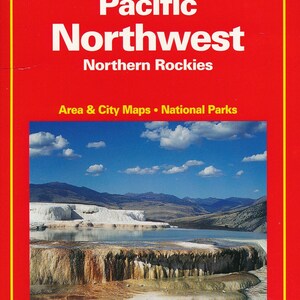 May include: A red cover of a USA Road Guide for the Pacific Northwest, featuring a photo of a natural hot spring with a blue sky and white clouds. The guide includes maps of the area and national parks. The cover also features the text "Hallwag" in yellow letters.