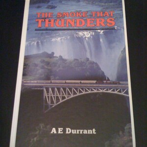 May include: A book titled "THE SMOKE THAT THUNDERS" by A E Durrant. The cover features a scenic image of a waterfall, a bridge, and a train. The title is in red letters, and the author's name is in white.