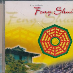 May include: A yellow CD case with a red and green octagon symbol with a yin yang symbol in the center. The text "A harmonia do Feng Shui" is at the top of the case. The text "Feng Shui" is written in a large, stylized font.