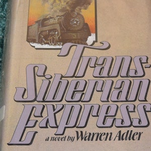 May include: A vintage book cover with a brown background and a purple title. The title is "Trans-Siberian Express" with the words "a novel by Warren Adler" below. The cover features a vintage illustration of a steam train with smoke coming from the chimney.