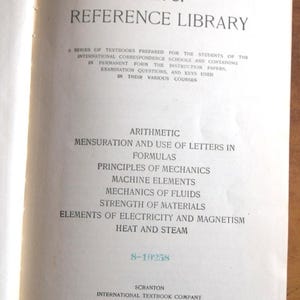May include: Open book page with text: "I.C.S. REFERENCE LIBRARY." Below, a list of subjects including Arithmetic, Mechanics, and Electricity. The book is from the International Textbook Company, Scranton. The page is off-white.