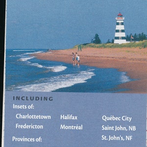 Puede incluir: Una cubierta de mapa azul y blanca con el texto "Atlantic Provinces Québec" y un logotipo AAA rojo. La cubierta también incluye un faro en una playa con personas caminando por la arena.