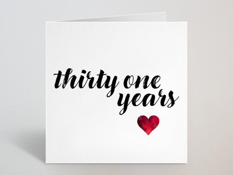 Puede incluir: Tarjeta de felicitaci&oacute;n blanca con las palabras "thirty one years" en escritura negra. Un coraz&oacute;n rojo de acuarela est&aacute; debajo del texto. La tarjeta est&aacute; doblada y tiene un dise&ntilde;o simple y elegante.