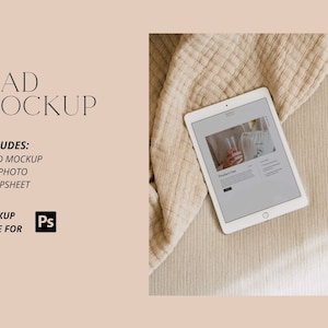 May include: A white iPad mockup on a beige blanket. The iPad screen displays a website with a photo of a person holding a glass of champagne. The text on the website reads "Product One".