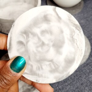 May include: A set of four white and gray marble coasters. The coasters are round and have a swirl pattern.