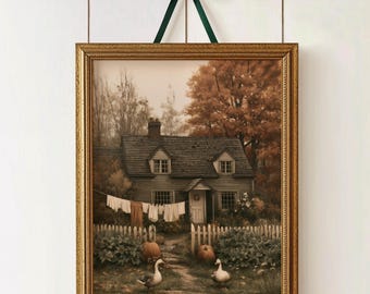 May include: A framed wall art print depicting a two-story house with a shingled roof, a white picket fence, and two geese in the front yard. Laundry hangs on a line near the house, and pumpkins sit on the ground. The frame is gold with a dark green ribbon.