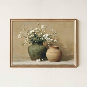 Puede incluir: Pintura enmarcada de naturaleza muerta con un jarrón verde lleno de flores blancas y un jarrón más pequeño, de color beige. La obra de arte tiene una paleta de colores cálidos y un marco dorado, evocando una estética vintage.