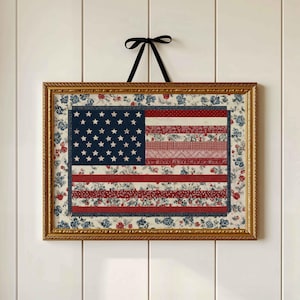 Vintage floral American flag wall art in a gold frame on a white paneled wall.