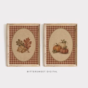 May include: Two rectangular framed wall art pieces featuring a brown and white gingham border. The left print displays a cluster of autumn leaves in shades of brown and green. The right print shows three pumpkins in orange and cream tones. Text reads BITTERSWEET DIGITAL.