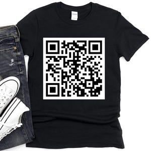 以下が含まれることがあります： 前面に白いQRコードが印刷された黒いTシャツ