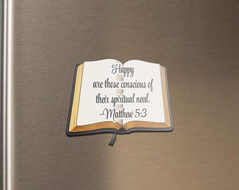 May include: A magnet shaped like an open book with the text "Happy are those conscious of their spiritual need. -Matthew 5:3". The book has a white interior, gold-colored edges, and a black border.