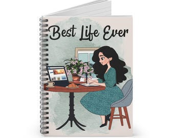 May include: Spiral-bound notebook with the words "Best Life Ever" on the cover. The cover illustration depicts a woman at a table with a laptop, coffee, and a croissant. A potted plant and a window are also visible.