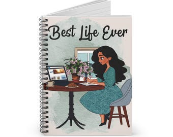 May include: Spiral-bound notebook with the text "Best Life Ever" on the cover. The cover features an illustration of a woman at a table with a laptop, coffee, and a croissant. A plant and a window are also depicted.