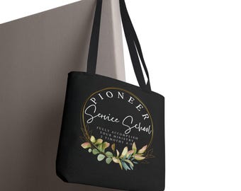 May include: A black tote bag with two shoulder straps featuring a circular gold-lined graphic. The text reads PIONEER Service School and FULLY ACCOMPLISH YOUR MINISTRY 2 TIMOTHY 4:5, accented by a watercolor-style botanical wreath of green and pink leaves.