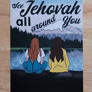 Op de afbeelding: Twee mensen zitten op een rots aan een meer en kijken uit over een bergketen. De tekst "See Jehovah all around you" staat in de lucht boven hen.