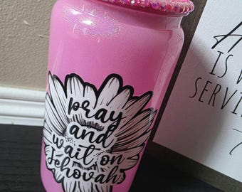 May include: Pink glitter tumbler with a floral design and the words "pray and wait on Jehovah." The rim is adorned with pink rhinestones. The tumbler is a vibrant, eye-catching accessory.