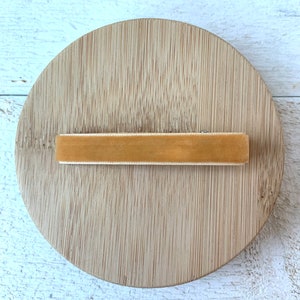 May include: A light brown velvet hair clip on a wooden surface.
