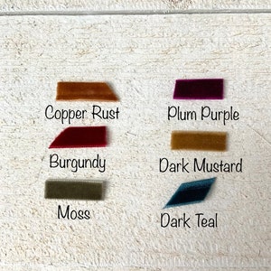 Puede incluir: Cinco muestras de tela en diferentes colores y texturas. Las muestras est&aacute;n etiquetadas como "Copper Rust", "Plum Purple", "Burgundy", "Dark Mustard" y "Dark Teal".