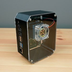 May include: A black and clear computer case with a small fan and multiple ports on the side.