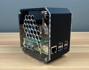 Op de afbeelding: Een zwarte acryl behuizing met een honingraatpatroon aan de zijkant. De behuizing heeft een transparant voorpaneel dat de interne componenten van een computer laat zien. De behuizing heeft verschillende poorten aan de achterkant, waaronder USB en Ethernet.